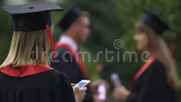 女毕业生在智能手机上发短信毕业典礼后放松视频的预览图