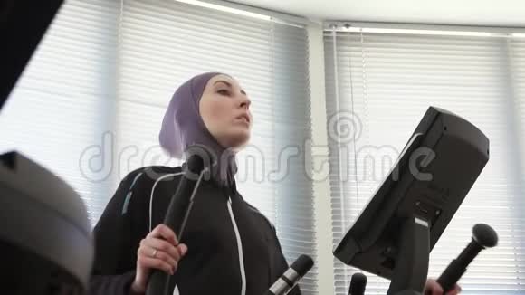 戴着头巾的漂亮女孩站在运动模拟器的台阶上视频的预览图