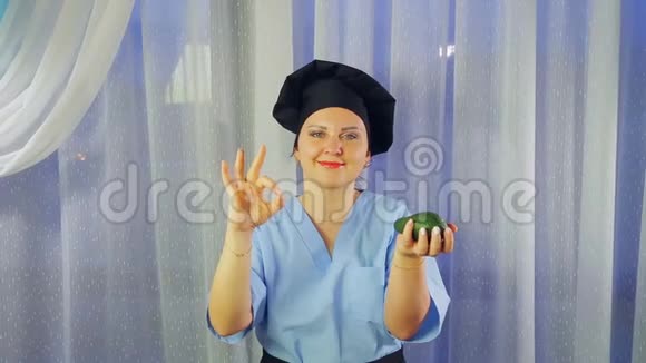 女人穿着围裙做饭微笑着手里拿着鳄梨用手表现得很好视频的预览图