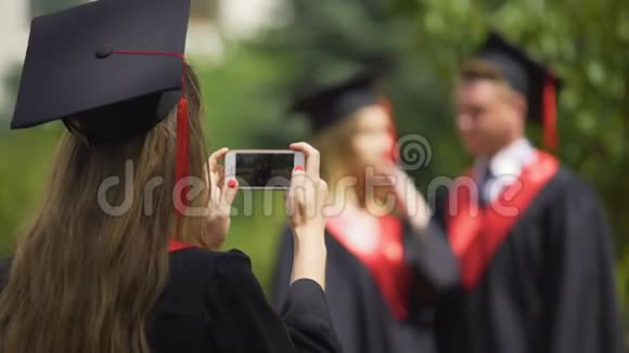 女毕业生用手机拍视频幸福的情侣摆姿势拍照视频的预览图