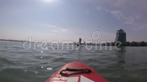 在冲浪板上划船男人在城市的SUP板上划桨视频的预览图
