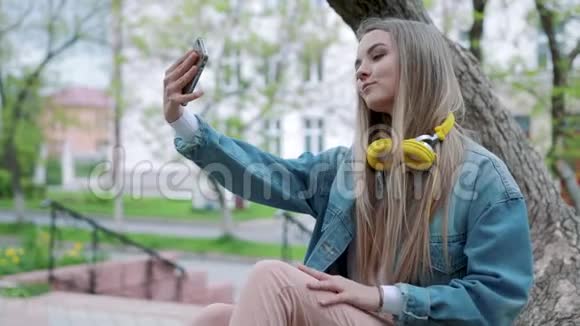 一位微笑的年轻女孩在公园拍自拍照片的肖像视频的预览图