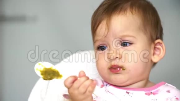 可爱的女婴拿着一个装有蔬菜的勺子一个孩子学勺子蔬菜从勺子上掉下来视频的预览图