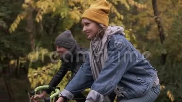 快乐微笑的朋友或年轻夫妇骑自行车穿过秋天公园男人和女人一起骑自行车视频的预览图