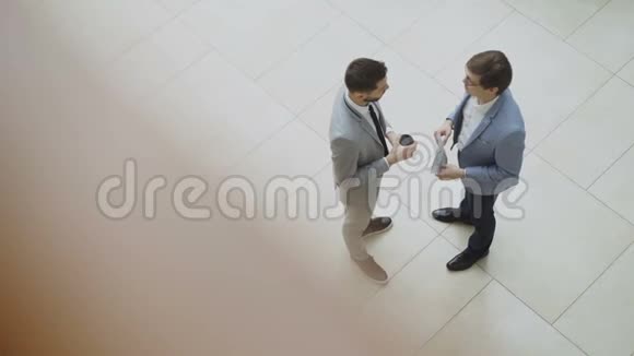两位商人在商务中心大厅聊天讨论财务报告的俯视图视频的预览图