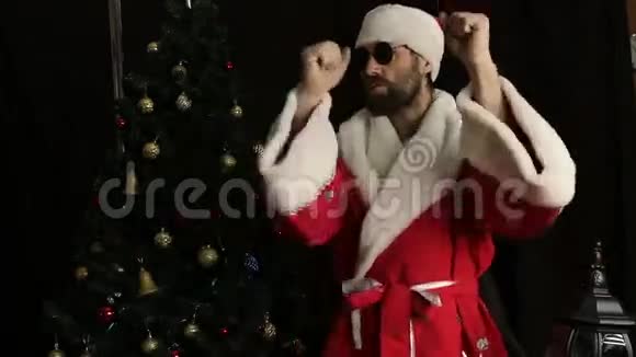 圣诞老人在圣诞树的背景下微笑着跳着滑稽的舞蹈视频的预览图