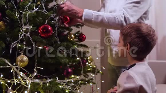可爱的小男孩和爷爷一起装饰圣诞树视频的预览图