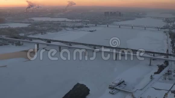 日落时冰冻河流的大城市工业区空中无人机视野视频的预览图