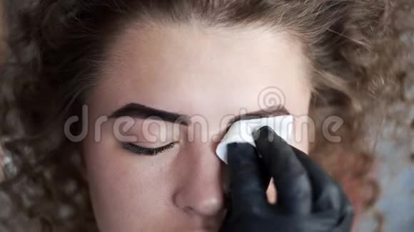化妆师在美容院用海绵擦拭眉毛然后进行眉毛着色和矫正视频的预览图