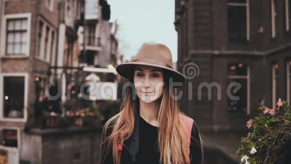 快乐的欧洲女孩看镜头的肖像漂亮的年轻女士戴着凉爽的帽子长发飘扬微笑4K视频的预览图