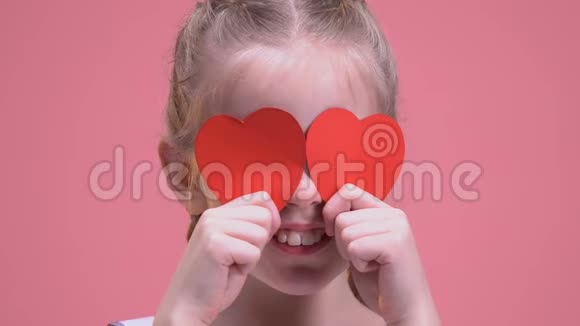 微笑的女孩用纸心闭上眼睛孤立在粉红色的背景上有趣视频的预览图