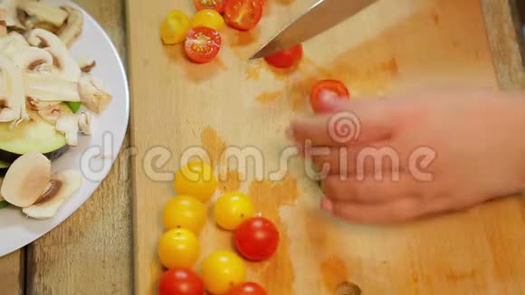 一个女人正在用一把刀切一个黄色和红色的樱桃番茄视频的预览图
