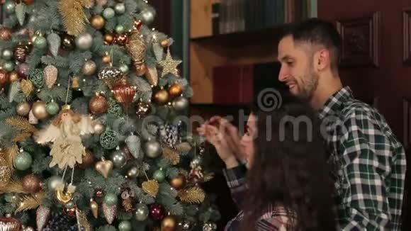 快乐的一对夫妇在家里装饰圣诞树视频的预览图