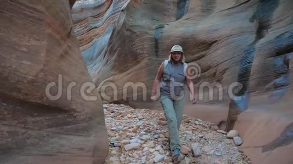 女子在干河峡谷徒步旅行峡谷4K的光滑和沉重的岩石视频的预览图