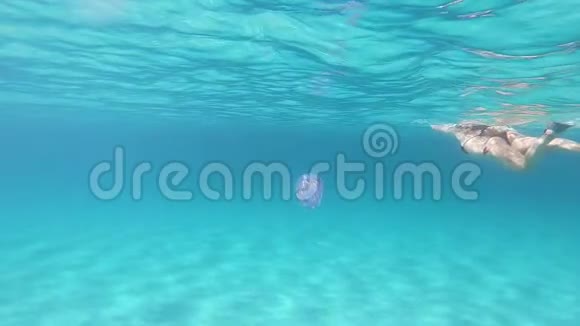 一位年轻美丽的女子在水下慢动作游泳她穿着透明的蓝色游泳身上有根瘤俗称视频的预览图