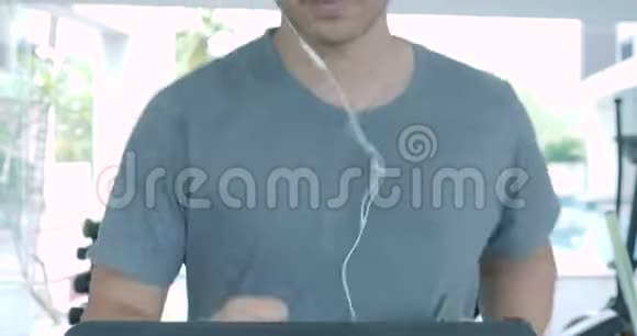 带着耳机在健身房跑步机上跑步的亚洲年轻人视频的预览图