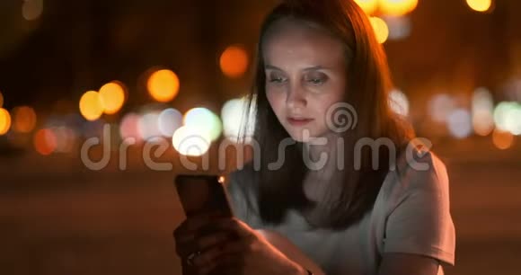 博克夜城年轻女性看智能手机屏幕视频的预览图