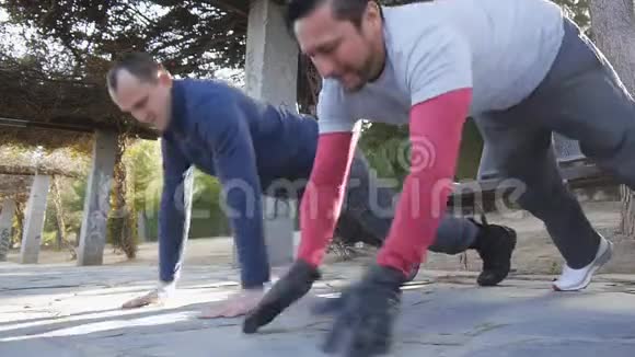与户外私人教练一起健身两个健身男子在公园里做拍手俯卧撑作为锻炼的一部分视频的预览图