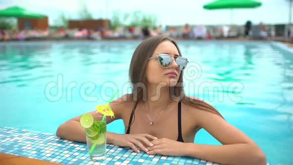 夏天美丽的年轻女子比基尼女孩在热带游泳池放松喝莫吉托鸡尾酒的女人视频的预览图