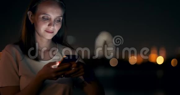 博克夜城年轻女性看智能手机屏幕视频的预览图