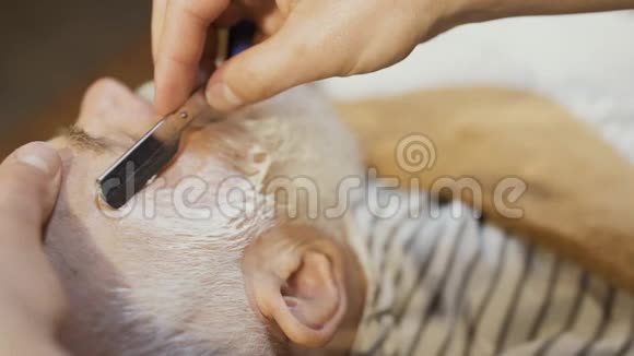 理发师用锋利的刀片刮胡子视频的预览图