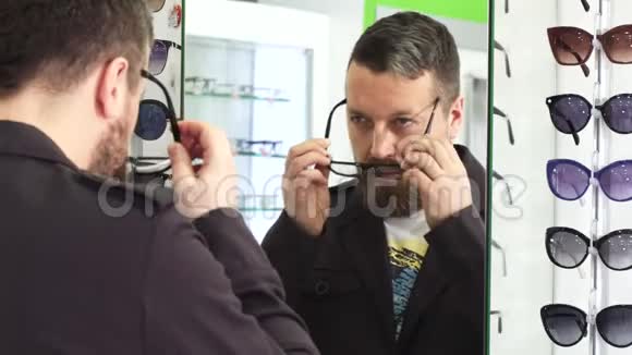 成熟的男人在前面试着戴新眼镜如果镜子在商店里视频的预览图