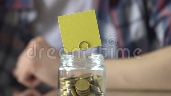 玻璃罐子上面的空贴纸上面有硬币钱换梦想储蓄概念视频的预览图