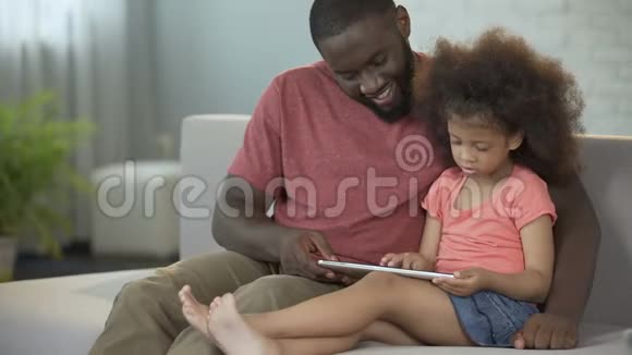 爸爸和女儿一起玩平板电脑的教育游戏视频的预览图
