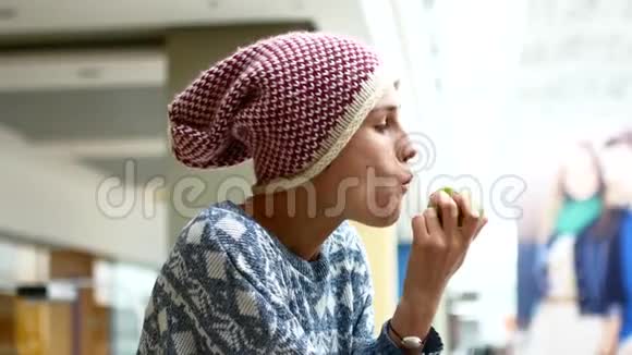 一个年轻的女人在商场里吃一个多汁的绿色苹果健康零食的概念视频的预览图