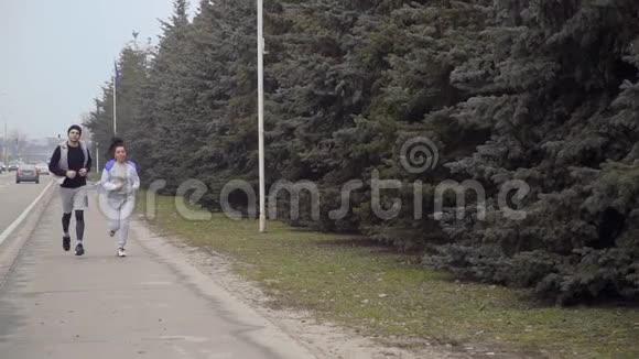 年轻女子和男子沿着城市道路奔跑视频的预览图