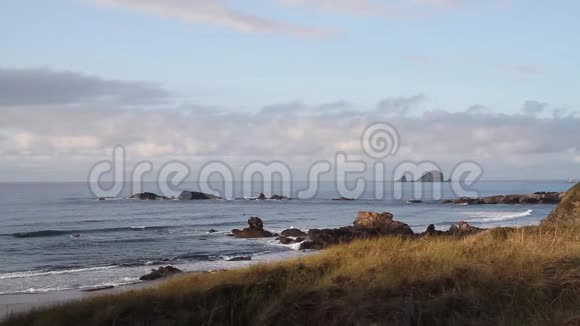 大西洋沿岸海中有岩石海浪蓝天有云前景有草日落时视频的预览图