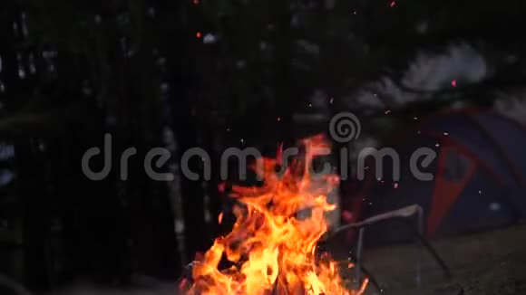 傍晚熊熊燃烧的篝火熊熊燃烧慢动作180fps在帐篷和游客的背景下着火视频的预览图