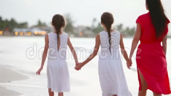 妈妈和孩子们在日落时散步一家三口沿着白色海滩散步视频的预览图