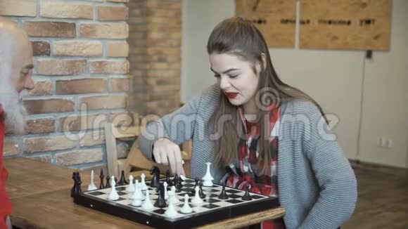 年轻漂亮的女孩和祖父下棋视频的预览图