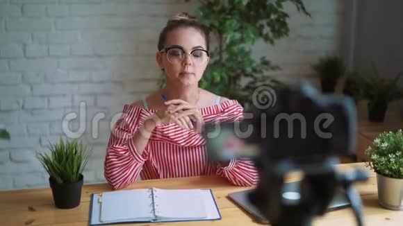 漂亮的女孩在办公室用相机录制视频时尚博客概念视频的预览图