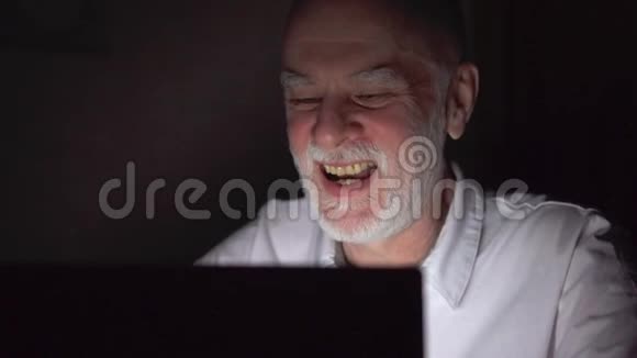 高级商人深夜在手提电脑上工作只有一张漆黑的脸视频的预览图
