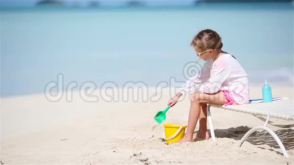 可爱的小女孩在海滩度假玩玩具孩子在日光浴下玩沙子视频的预览图