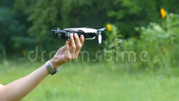 人类手握着无人机或四架直升机在绿色森林的背景下飞行未来视频的预览图