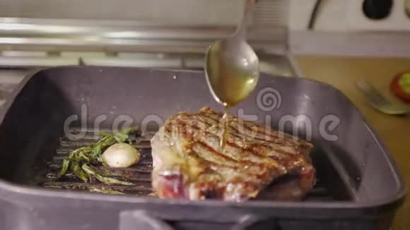 在热黑锅上用迷迭香和大蒜烤一份牛肉牛排然后用勺子油倒进去视频的预览图