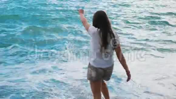 美丽的年轻姑娘玩着大海的浪花视频的预览图