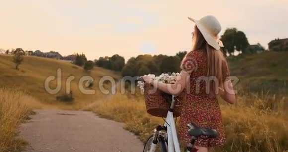 背部计划美丽的金发女郎穿着礼服复古自行车在夏天的田野上行走视频的预览图