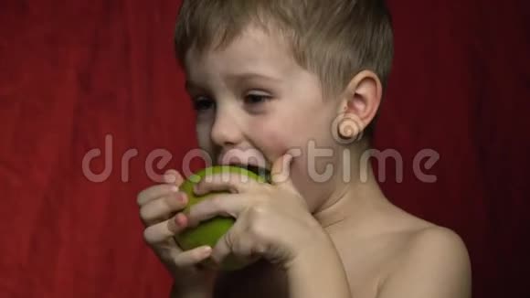 一个快乐的男孩咬一口绿色的苹果视频的预览图