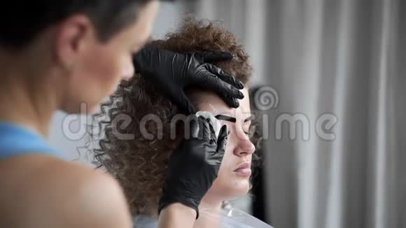 化妆师在美容院用海绵擦拭眉毛然后进行眉毛着色和矫正视频的预览图