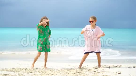可爱的小女孩在海滩上玩得很开心两个漂亮的孩子在海滨跳舞视频的预览图