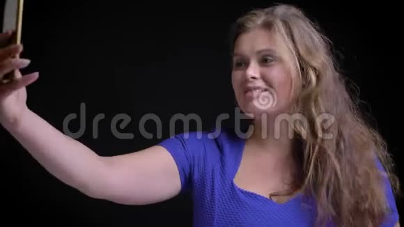 在镜头前微笑摆姿势的电话中拍摄白种人成年女性自拍的特写镜头视频的预览图
