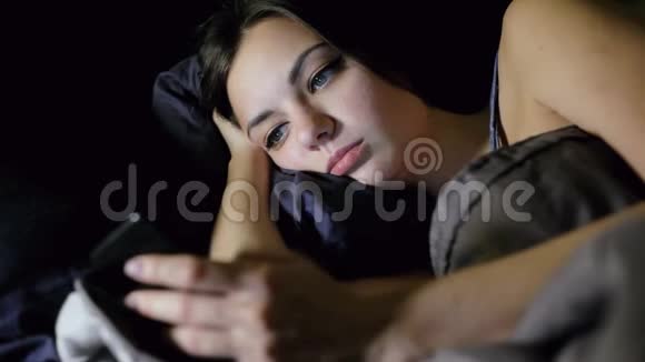 女人晚上躺在床上上网看照片聊天视频的预览图