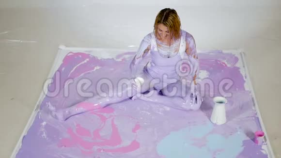 紫色颜料的女瑜伽坐在画好的画布上视频的预览图