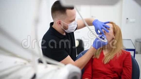 牙科医生柜中的女病人在手术期间进行口腔卫生牙科治疗视频的预览图