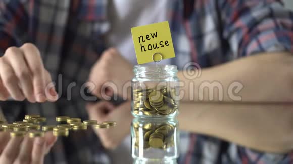 带钱的玻璃瓶上面的新房子短语储蓄概念搬家移民视频的预览图