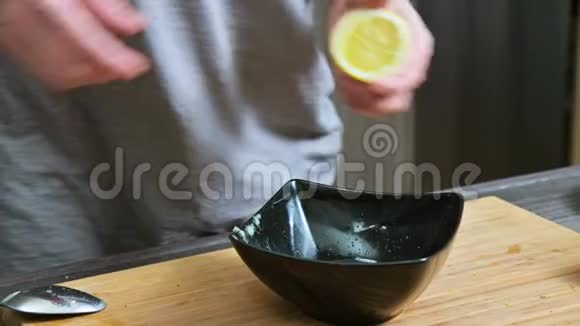 特写女孩用叉子挤用柠檬在黑碗里做酱汁视频的预览图